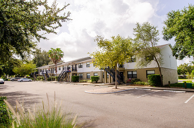 Disston Place Apartments exterior with trees and parking lot.