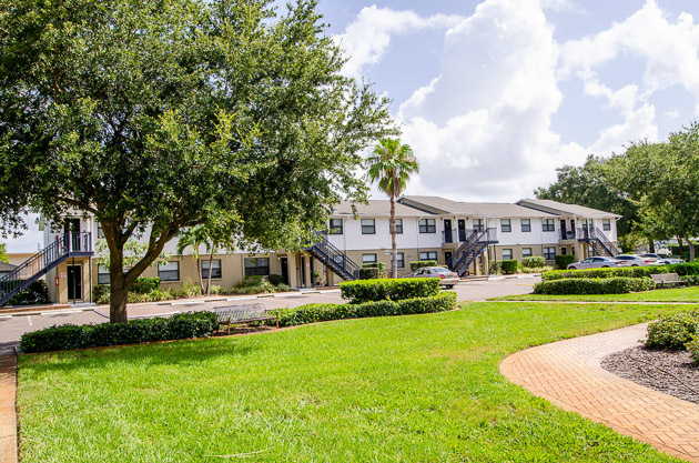 Disston Place Apartments exterior with trees and green grass.