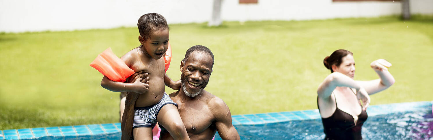 dad playing in pool with young son