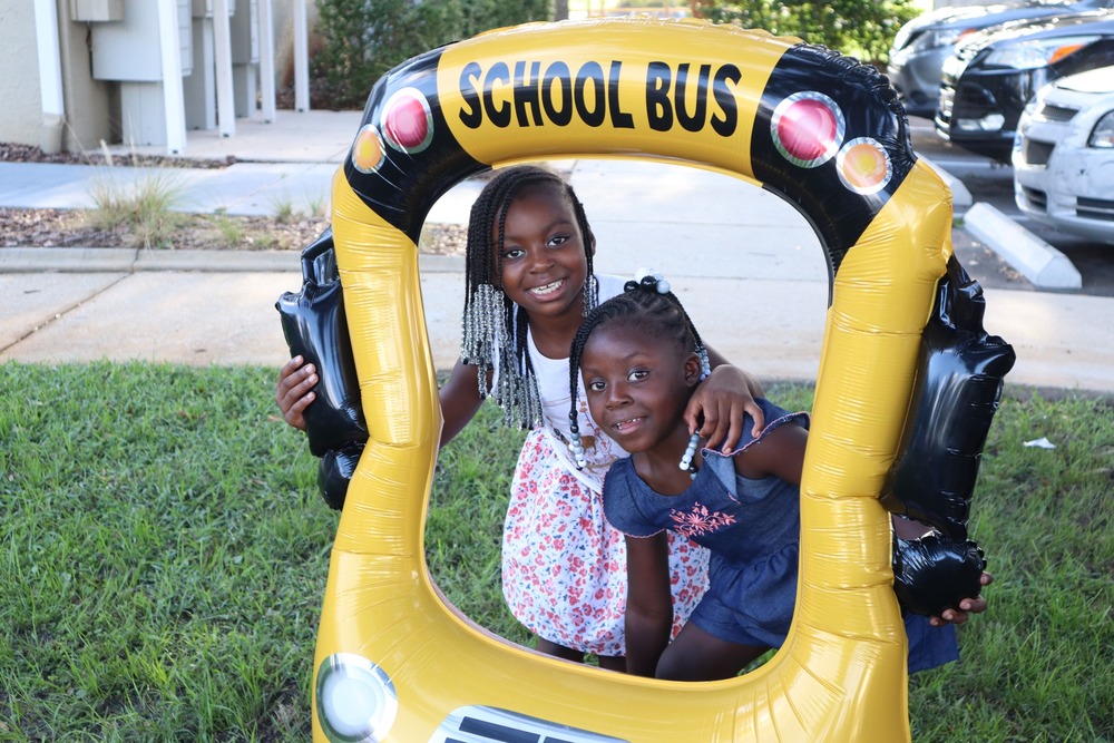 Image of two kids with school bus balloon at Disston Place Apartments Back to School event.