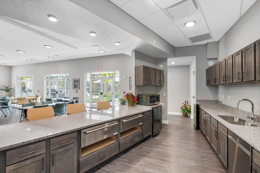 Downstairs community room kitchen with cabinets inside The Legacy at Jordan Park senior midrise building.