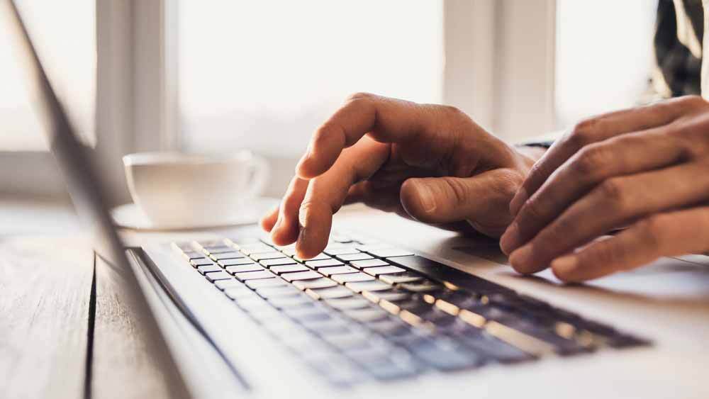 Hands typing on a laptop keyboard.