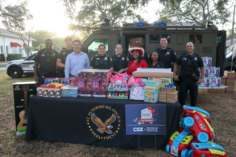 St. Petersburg Police Department (SPPD) officers with St. Petersburg Housing Authority (SPHA) members standing by a table full of toys.