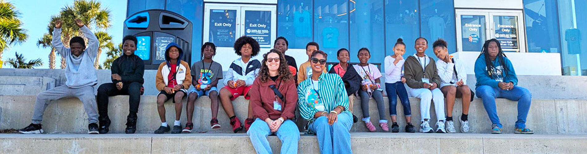 Students and teachers sitting on concrete stairs in front of STEM building