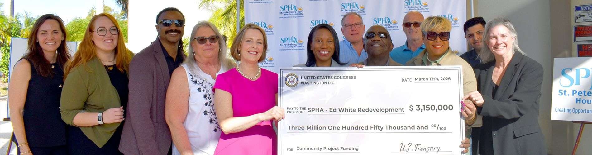 Twelve individuals posing with a check that is written out to the Edward White Redevelopment for three million one hundred and fifty thousand dollars.