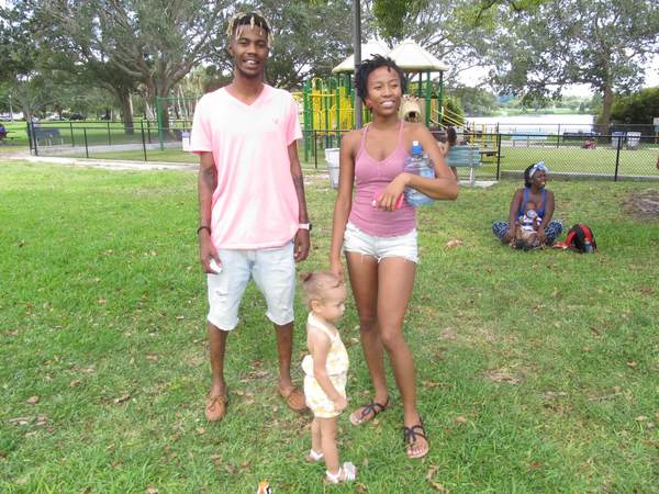 Family standing on green grass at Family Fun Day event in Crescent Lake Park.
