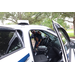 Policeman giving a tour of his police car with a young child looking at the ceiling of the car.