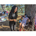 Child sitting under tree, having her face painted.