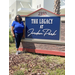 Pinellas County Commissioner Rene Flowers standing next to exterior entrance sign of The Legacy at Jordan Park.