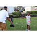 Adult holding a bubble machine and a child playing with bubbles outside in the grass at Disston Place Apartments.
