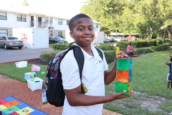 Young boy holding a toy and wearing a backpack at Disston Place Apartments Back to School Event 2023.