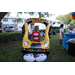 Child wearing red shirt smiling and standing behind a balloon school bus at Disston Place Apartments Back to School Event 2023.