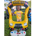 Child wearing yellow shirt smiling and standing behind balloon school bus.