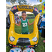 Child wearing green shirt standing behind a balloon school bus at Disston Place Apartments Back to School Event 2023.