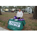 Person standing by USF St. Petersburg table at Very Merry Holiday Party in Jordan Park.