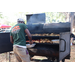 Cutting Edge Landscape &amp; Nursery person in green shirt preparing BBQ at the Spring Family Picnic event in Jordan Park on March 26, 2024.