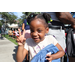  Young girl holding a backpack with her left hand and making the peace symbol hand gesture with her right hand. 