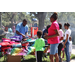  SPHA team member wearing a blue shirt and a group of people at backpack table at Back to School Event in Jordan Park 2025. 