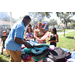  People at backpack table at Back to School Event in Jordan Park with green grass in the background. 