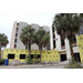  Exterior of The Edward White Campus with exterior walls under construction, and palm trees. 