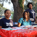  Three people at a red table at the Very Merry Holiday Party in Jordan Park. 
