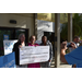  Carolyn Avington, SPHA Vice President of Finance / CFO, U.S. Rep. Kathy Castor, and Danielle Thomas, SPHA Sr. Vice President / COO holding a big check, with a photographer taking their photo. 