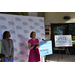  U.S. Rep. Kathy Castor speaking at a microphone, with Danielle Thomas, SPHA Sr. Vice President / COO, standing next to her, with a background of the SPHA logo repeating. 